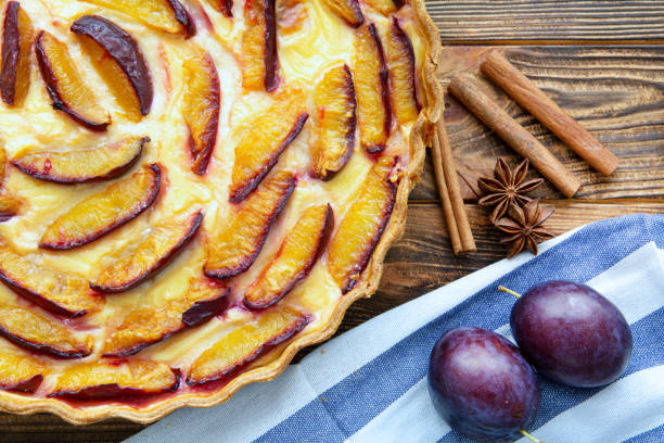 istock Fruit cake with cream and plum on rustic background, top view. 1221707796