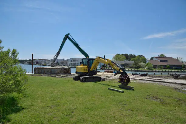 A bulkhead in a marina in Ocean Pines, Maryland on a warm spring day.  Heavy equipment is present as are materials used in the project.