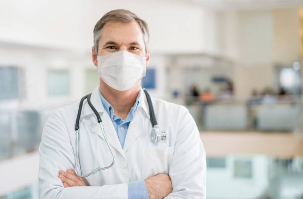 Happy doctor working wearing a facemask to avoid COVID-19 Portrait of a happy doctor working wearing a facemask to avoid COVID-19 â Pandemic concepts epidemiology photos stock pictures, royalty-free photos & images