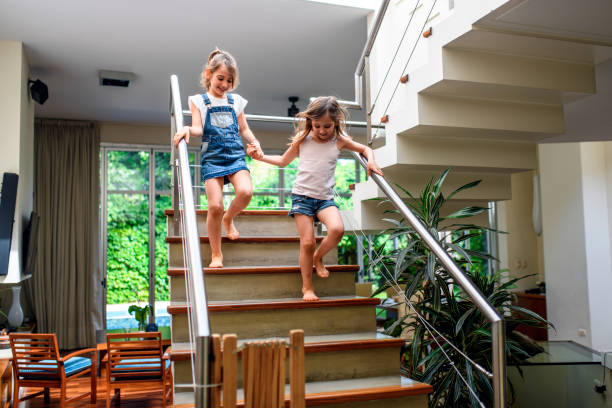 istock Sisters Holding Hands and Taking Careful Steps Down Stairs 1221713893