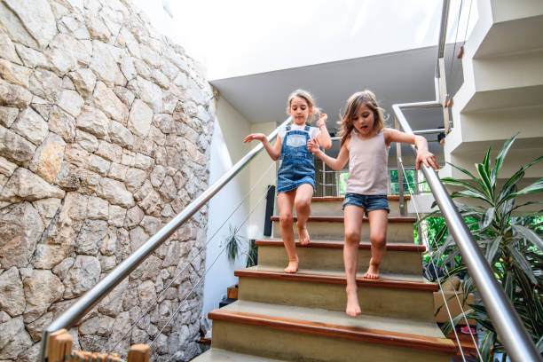 istock Sisters Hurrying Down Stairs in Modern Home 1221713895