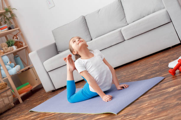 istock Charming and junior girl making sport exercise at home 1221714164