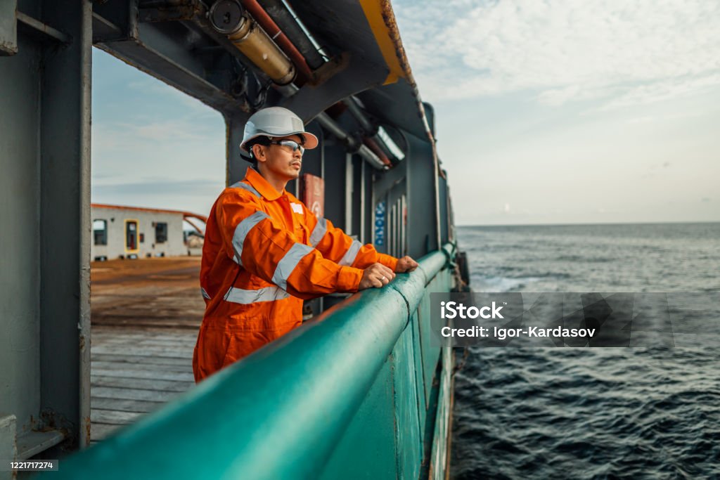 Filipino deck Officer on deck of vessel or ship Filipino deck Officer on deck of vessel or ship , wearing PPE personal protective equipment - helmet, coverall, lifejacket, goggles. Safety at sea. He is tired Ship Stock Photo