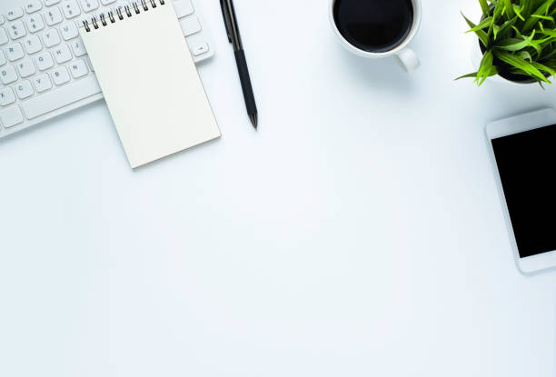 istock Workplace in office with white desk. Top view from above of keyboard with notebook and coffee. Space for modern creative work of designer. Flat lay with blank copy space. Business and finance concept. 1221721795