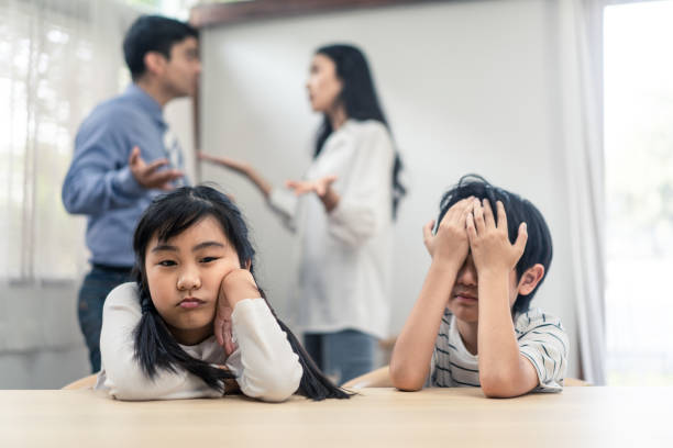 deux jeunes enfants se sentant tristes et ennuyeux en raison des parents se battant à la maison. la sœur aînée se sent déçue et frère frère frère pleure sur le père et la mère des ennuis agressifs. problème malheureux dans la famille - unemployment fear depression women photos et images de collection