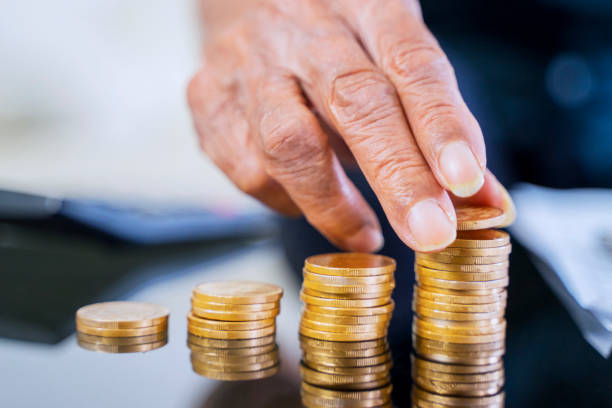 istock Elderly man hand stacking golden coins on table 1221730502
