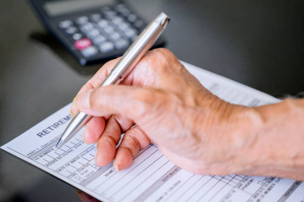 istock Hand filling retirement claim application 1221730546