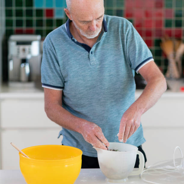 istock Senior man in domestic kitchen mixing a fruit cake 1221734342