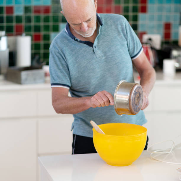 istock Senior man in domestic kitchen mixing a fruit cake 1221734351
