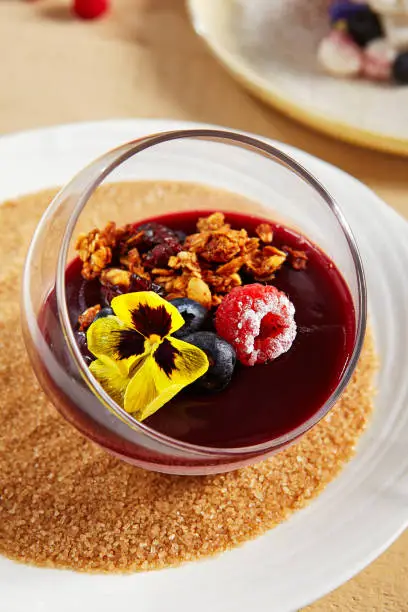 Berry Panna Cotta with Currant-Cointreau jelly in glass bowl. Creamy dessert with berries close up. Sweet meal, raspberry and blackcurrant souffle. Served gourmet appetizer, delicious restaurant food