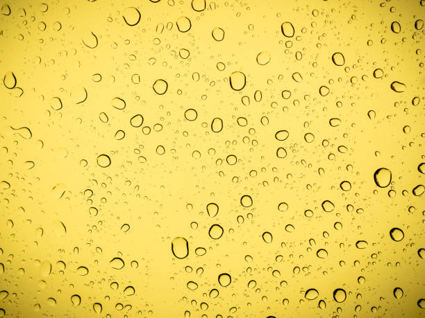 Raindrops on a yellow glass, abstract yellow background. stock photo