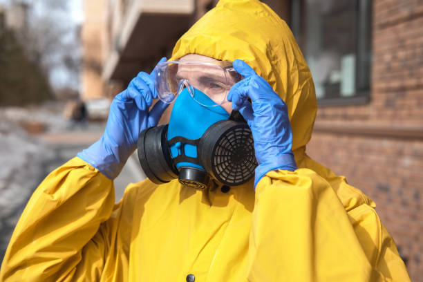 Virologist in a protective yellow suit and a respirator on the streets of the city. The doctor is wearing goggles, gloves, and a mask. Virologist in a protective yellow suit and a respirator on the streets of the city. The doctor is wearing goggles, gloves, and a mask. biohazard cleanup stock pictures, royalty-free photos & images