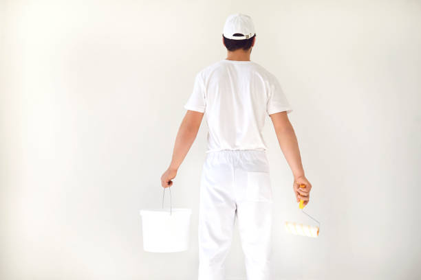 istock A male painter in a white uniform with a roller works in his hand in a white room 1221743199