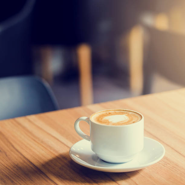 istock Latte Coffee in a cup on wooden table and Coffee shop blur background 1221746076