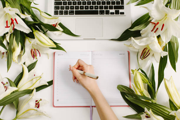istock A woman writing in her notebook. Workspace with omputer which surrounded with green flowers and leaves. Flat lay, top view 1221748277