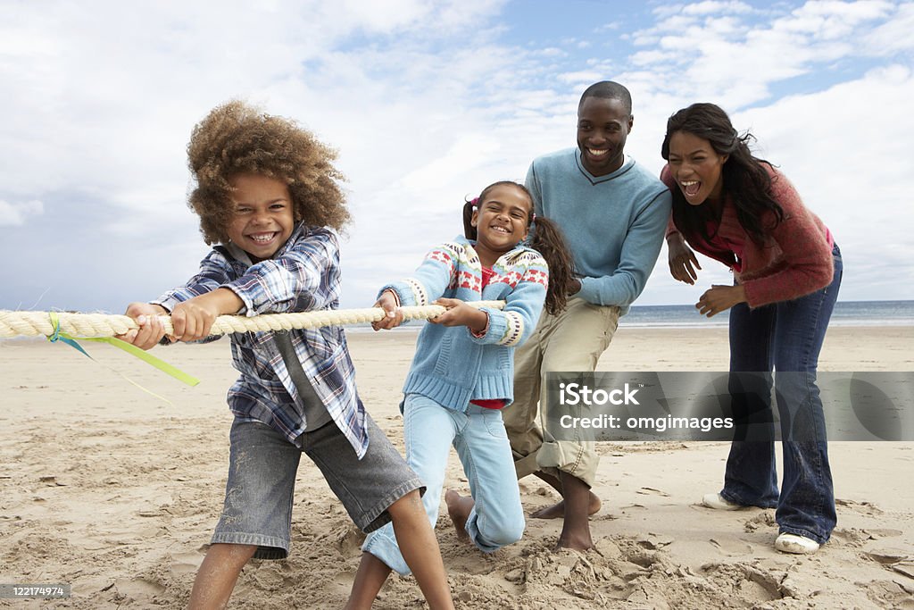 Famille jouant tirer de la guerre sur la plage - Photo de Tir à la corde libre de droits