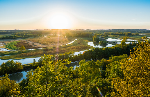 Beautiful view of Missouri River floodplain at sunset in fall; water in the fields; distant woods and sky in background