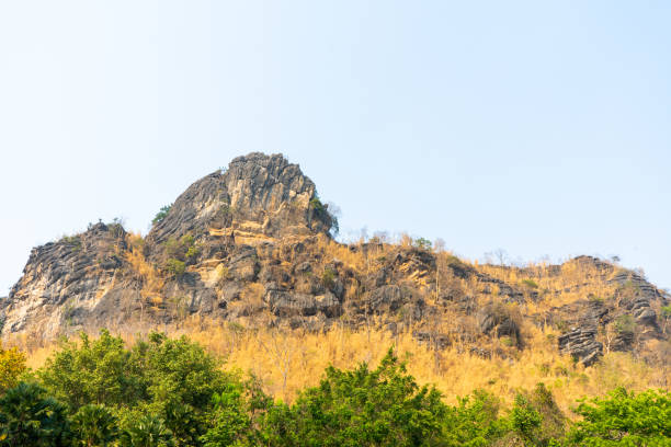 istock Limestone mountain peak At the bottom there is a yellow grass. And green trees With a beautiful sky 1221750580
