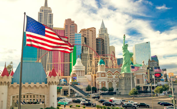 The Stars and Stripes blowing in the breeze in front of the New York New York Hotel and Casino as the rollercoaster goes past - Las Vegas, Nevada, USA