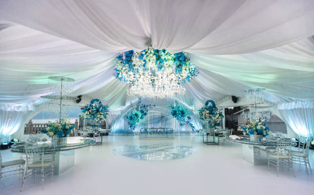 Wedding ceremony in a beautiful tent. Hall with dining tables decorated with bouquets of flowers.