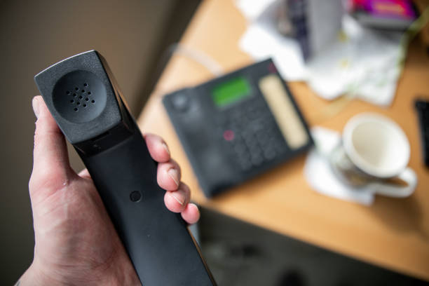 Office phone, handset in hand, answers the call