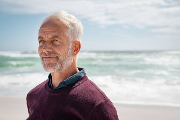 uomo anziano soddisfatto pensando in spiaggia - serene people one man only men contemplation foto e immagini stock