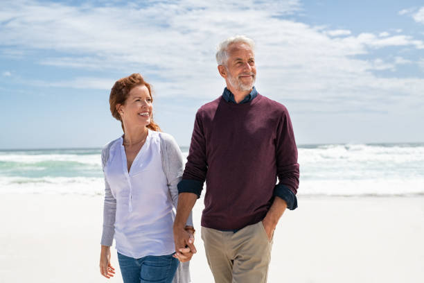 seniorenpaar zu fuß am strand im herbst - holding hands human hand holding couple stock-fotos und bilder