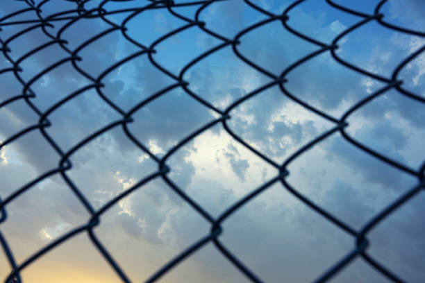 Mesh fencing steel over clouds sky background.