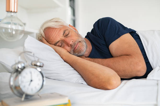 Senior man sleeping Old tired man sleeping on bed at home. Senior man with white hair in deep sleep on soft pillow at home. Mature healthy guy lying on side resting at home while sleeping. old man pajamas photos stock pictures, royalty-free photos & images