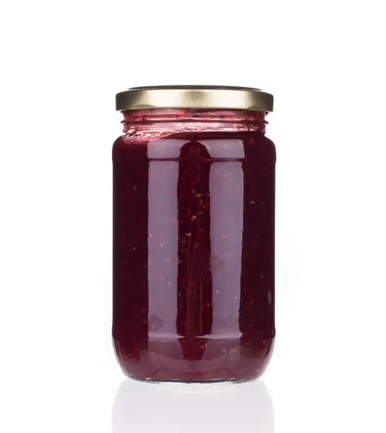 Glass jar with berry jam. Isolated in a white background. Close-up.