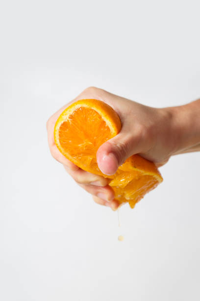 istock Strong female hand pressing orange half isolated on white 1221757933