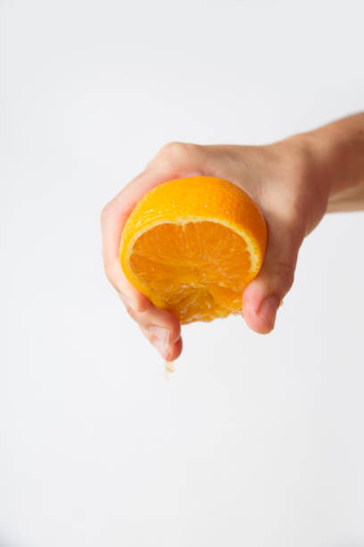 istock Strong female hand squeezing orange half isolated on white 1221757966