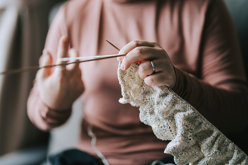 an asian chinese mid adult woman at living room knitting during her free time leisure activity