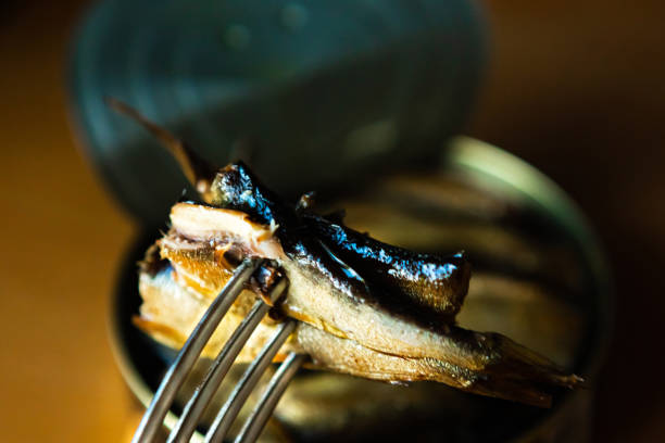 sprats in oil impaled on a fork