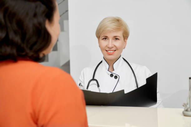 istock Patient and doctor holding folder behind reception. 1221765604