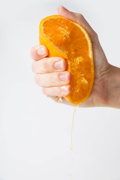 istock Hand of woman squeezing orange half 1221765694