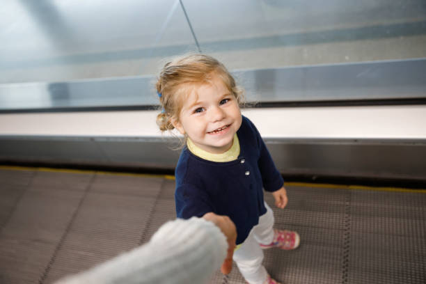 adorável garotinha no aeroporto. adorável criança caminhando para o portão e indo em férias em família de avião. criança feliz positiva. - escalator child shopping mall little girls - fotografias e filmes do acervo