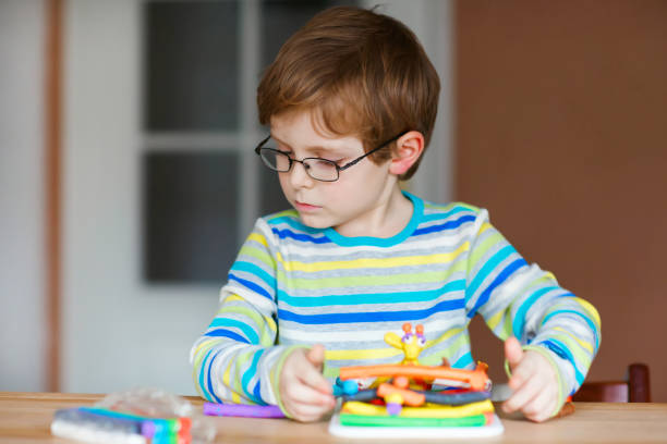 istock Smiling preschool kid boy having fun with dough, colorful modeling compound clay. Creative leisure with children. during corona virus quarantine staying at home. Shelter in place, lockdown concept, 1221767312