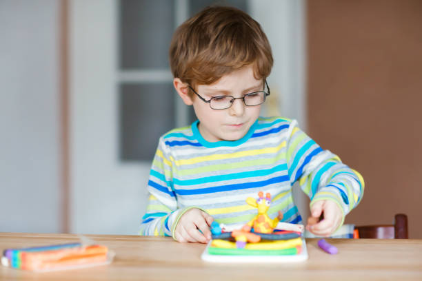 istock Smiling preschool kid boy having fun with dough, colorful modeling compound clay. Creative leisure with children. during corona virus quarantine staying at home. Shelter in place, lockdown concept, 1221767330