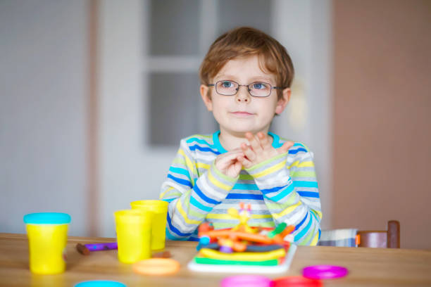istock Smiling preschool kid boy having fun with dough, colorful modeling compound clay. Creative leisure with children. during corona virus quarantine staying at home. Shelter in place, lockdown concept, 1221767345