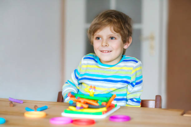 istock Smiling preschool kid boy having fun with dough, colorful modeling compound clay. Creative leisure with children. during corona virus quarantine staying at home. Shelter in place, lockdown concept, 1221767365