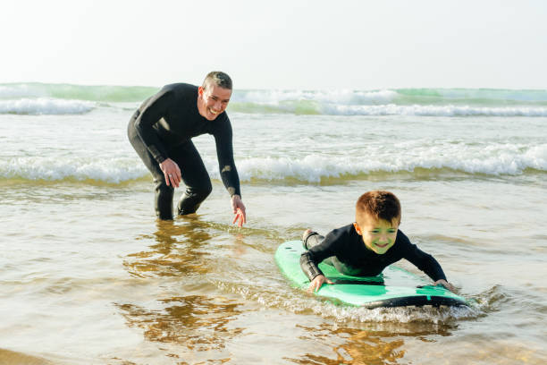 istock Father teaching son surfing in ocean 1221767913