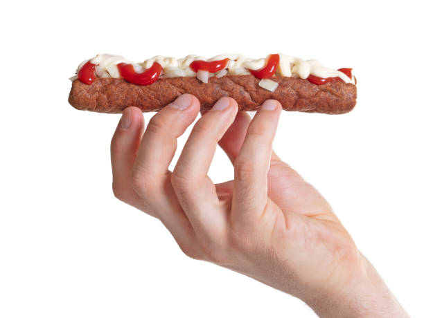 Man eating a frikadel with ketchup, mayonnaise on chopped onions, a Dutch fast food snack called 'frikadel speciaal'