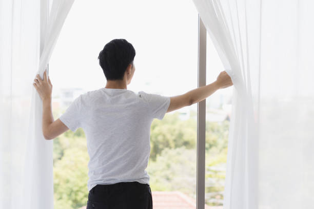 istock Man open the curtain and look outside the window. 1221768746