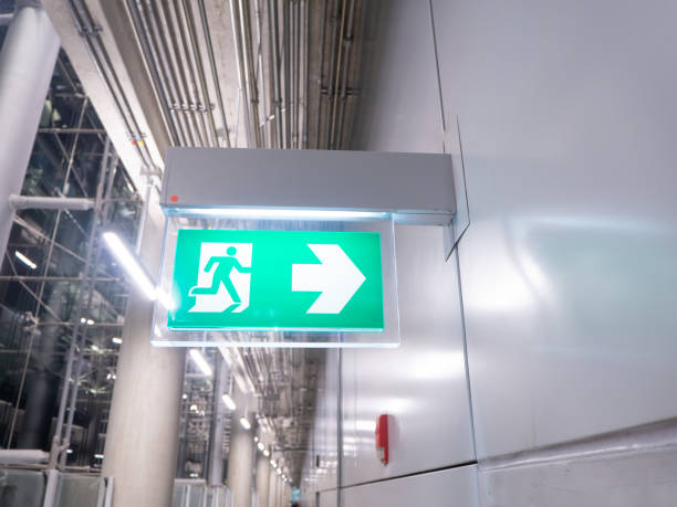 istock led sign in corridor point way out of resident apartment building, Fire warning exit with arrow symbol sign box light Emergency Exit 1221769471