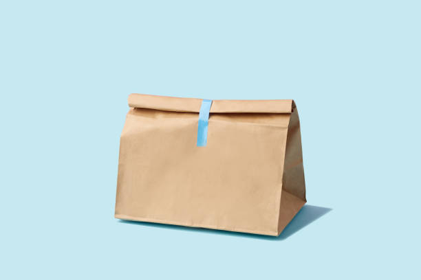 Brown clear empty blank paper bag for food delivery on blue background with copy space. Packaging template mock up fast food.