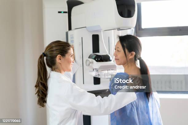 Female Doctor Talking To Her Patient And Adjusting Her Position To Do A Mammogram Stock Photo - Download Image Now