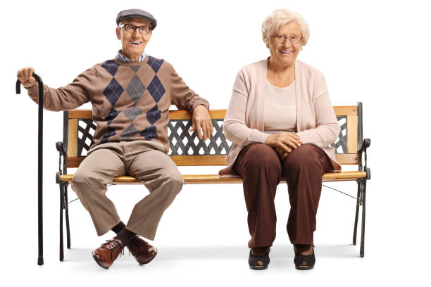 istock Seniors smiling and sitting on a bench isolated on white background 1221771052
