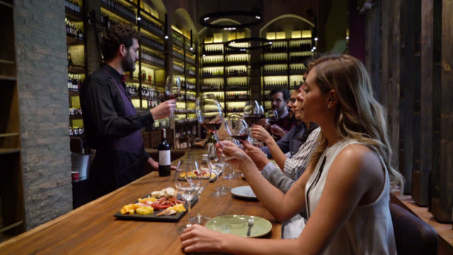 Latin American sommelier teaching a group of people about a wine while they look at the texture in glass