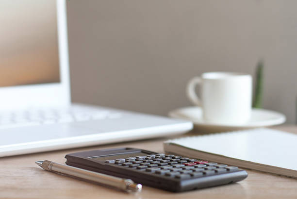 Home office workspace desk with laptop, headphones, pen, diary, blank, notepad, shell, calculator, cup on wooden table background. Flat lay, top view. Minimal workspace, business concept
